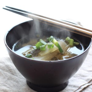 Steaming bowl of soup with chopstiks on top.
