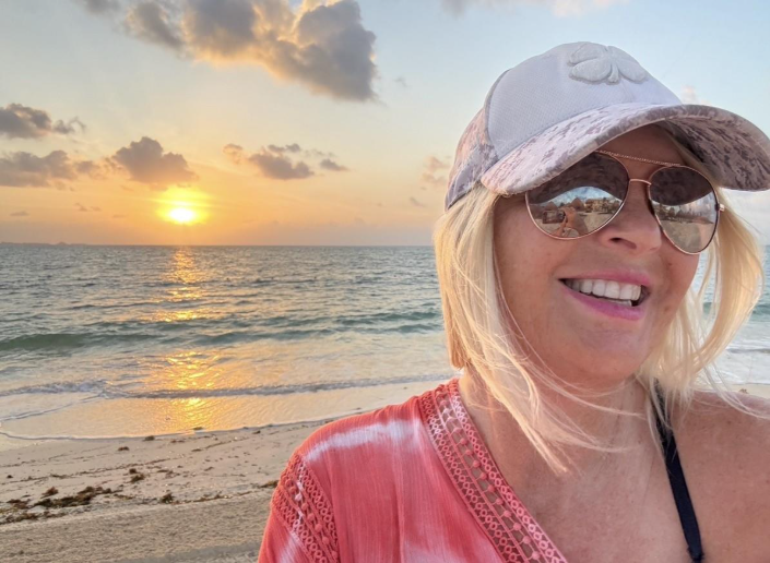 Woman at beach with sunset behind her